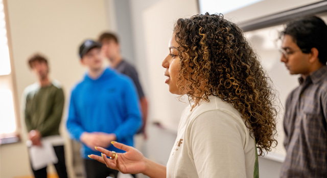 A student in a group gives a presentation in front of her class.