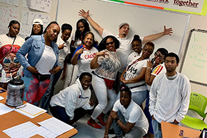 A group of students at the Academy of Hope Adult Charter School standing in front of a whiteboard