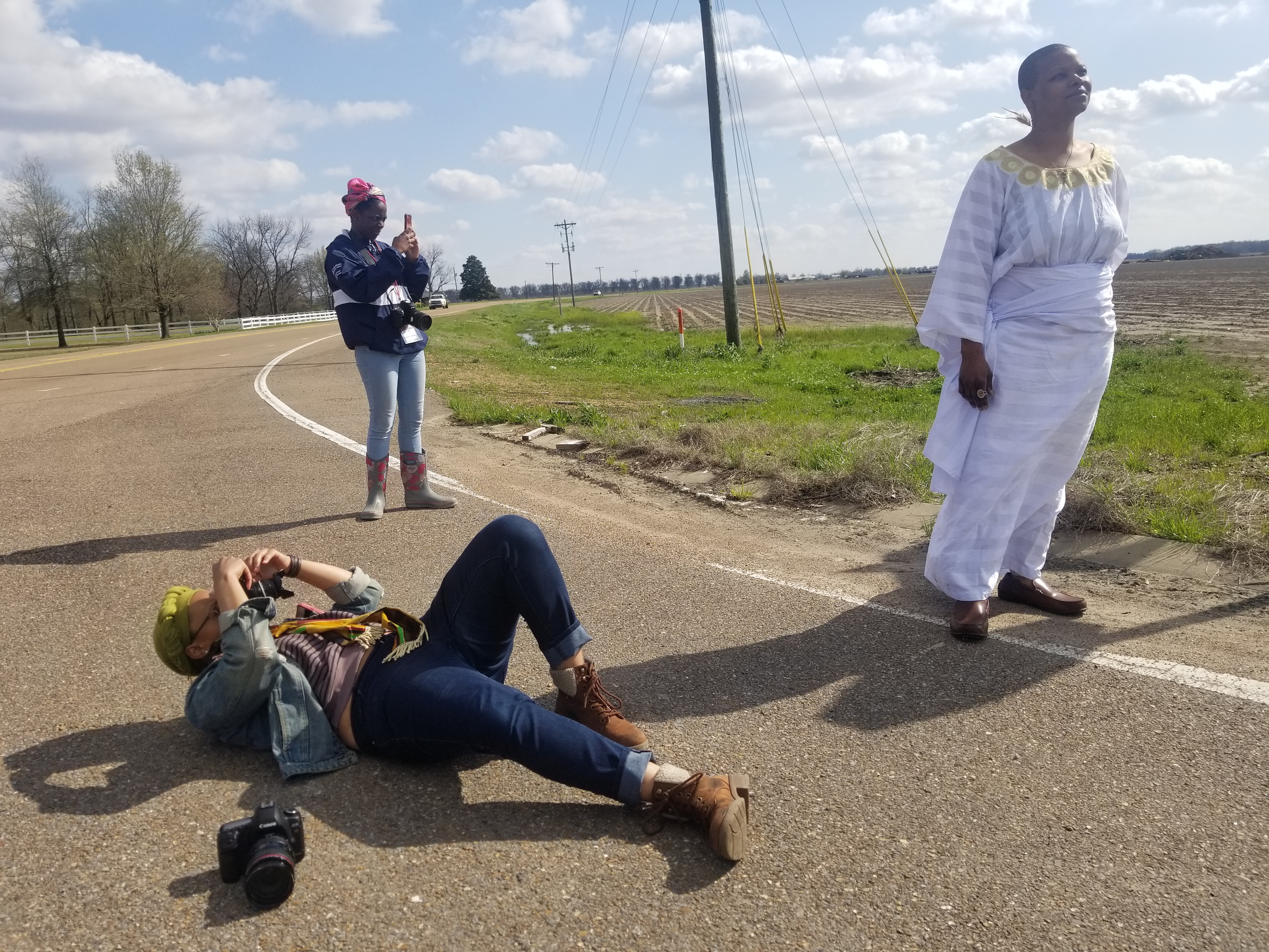 Shumate lays down on the New Africa Road in Clarksdale, MS filming Chandra Williams, Director of the Crossroads Cultural Arts Center