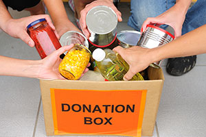 People putting food items into donation box