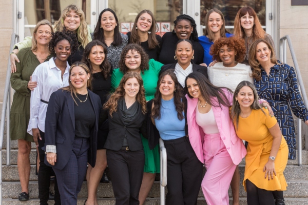 18 professional women hugging on outdoor stairs