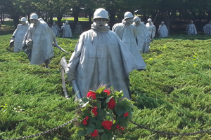 Korean War Memorial with statues of soldiers; a red rose wreath in front