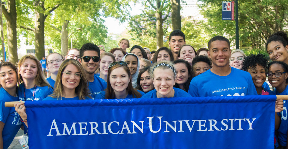 Students hold an American University banner during orientation.