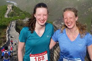 Two women in running clothes, standing at the Great Wall of China.
