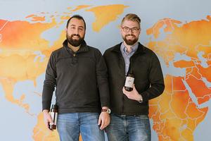 Two men posing in front of world map.