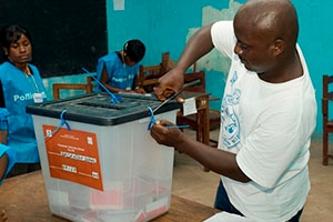 A Liberian election worker opens a ballot box.