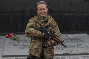 Ukrainian woman holding a rifle in military fatigues.