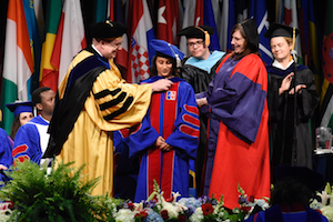 Anila (middle) is hooded during graduation by her mentor Stoodley (right).