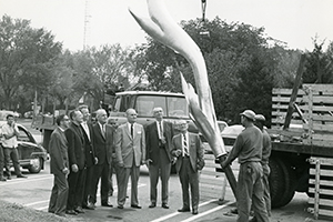 Men review the Kay Center’s 14 foot bronze flame before it is placed on building