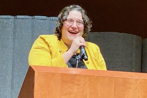 Author wearing yellow jacket, speaking.
