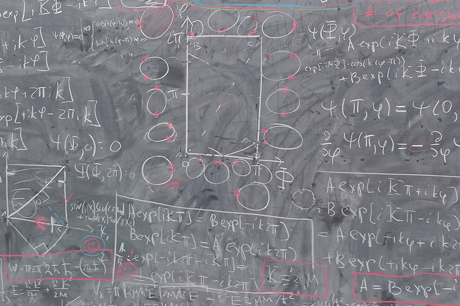 A chalkboard filled with equations and writing.